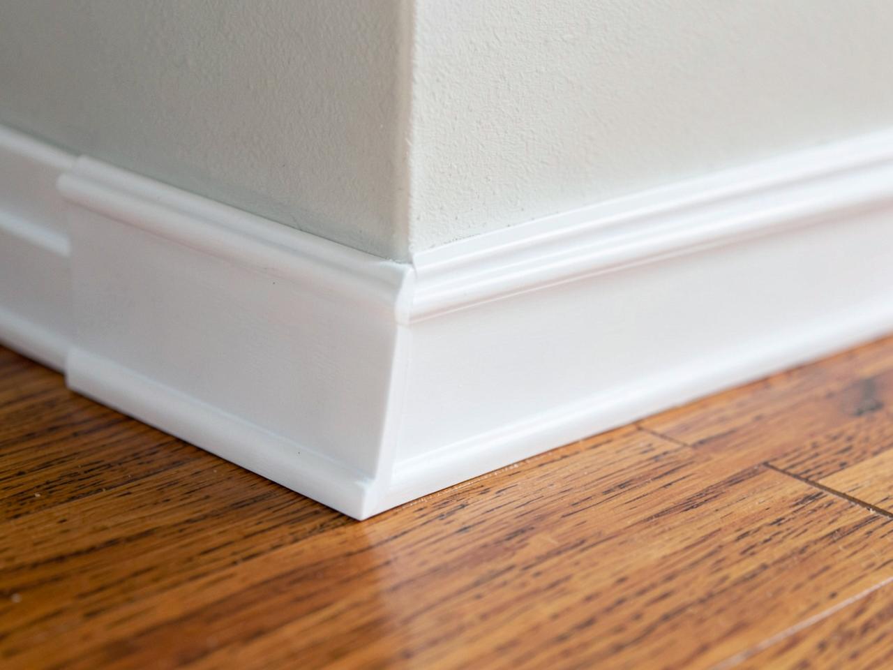 Detail of crisp white baseboard and shoe moulding meeting a warm hardwood floor