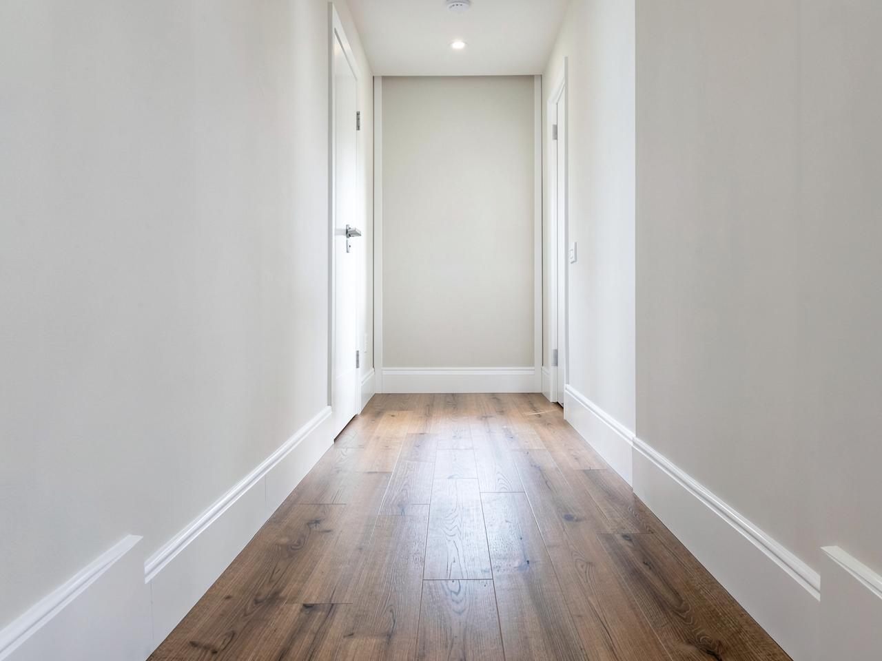 Bright modern hallway with wood-look plank flooring and clean white baseboards